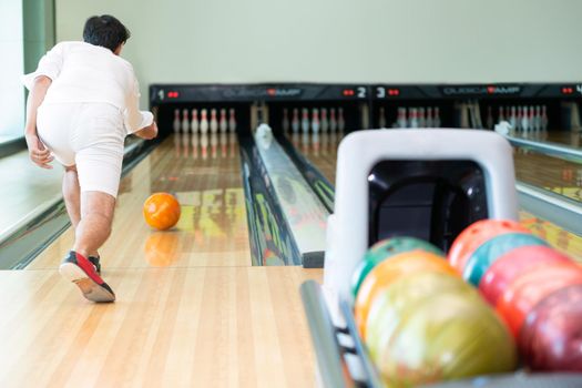 Young man playing bowling at the sport club.