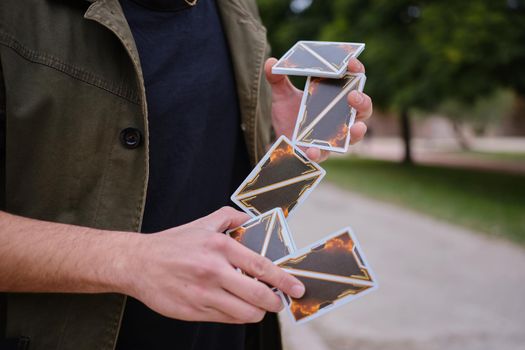 Cropped photo with selective fotos of the hands of a street magician shuffling the cards in the street