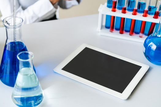 Tablet computer in laboratory and biochemistry sample in test tube. Science technology research and development study concept.