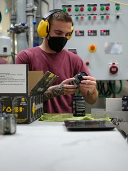 Vertical photo of a man with headphones reading the label on a can before packing it for shipment