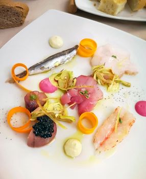 Italian food, fresh fish with carrots, artichokes and sauces