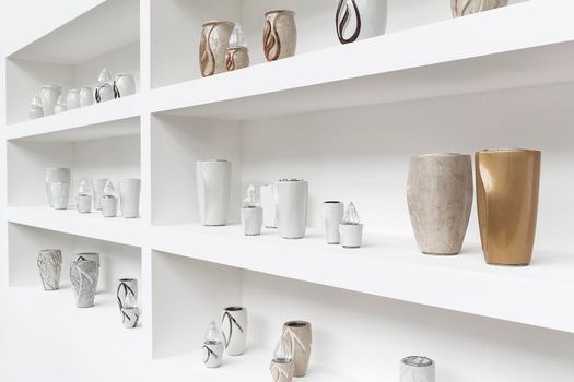 Exhibition of funerary urns, propped on a shelf white.