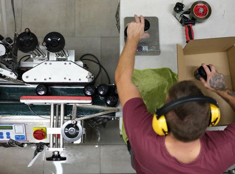 Top view of a worker packing cans of beer for a deliver while sitting on a table in a factory