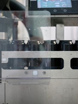 Vertical photo through glass of beer cans on a platform on the packaging line of a brewery.