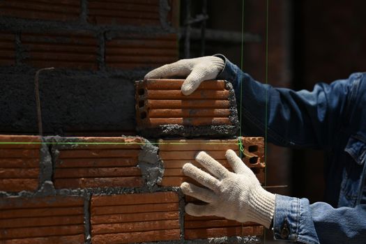 Close up of bricklayer installing bricks on construction site. Concept of repair and building materials.