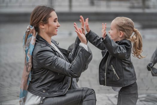 mother plays with her daughter in the city on the square