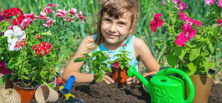 A little girl is planting flowers. The young gardener. Selective focus. nature.