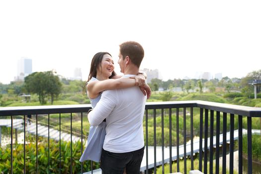 Multiethnic couple in love cuddling in a viewpoint of an urban park during sunset