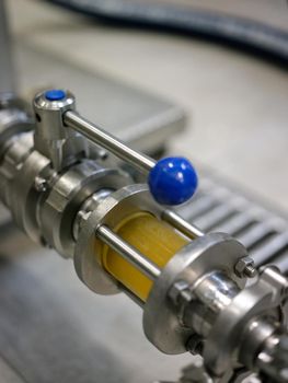 Vertical photo of the detail of a piece of pipe with craft beer inside in a beer canning factory