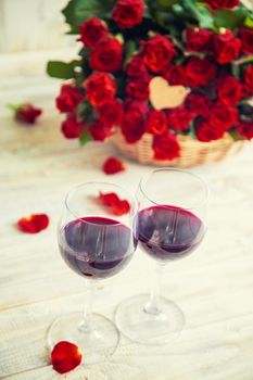 A bouquet of red roses and red wine in glasses. Valentine's Day. Selective focus. Holiday.
