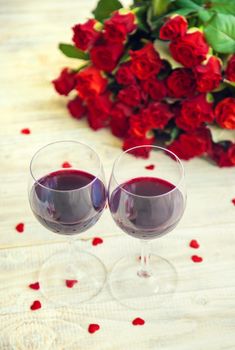 A bouquet of red roses and red wine in glasses. Valentine's Day. Selective focus. Holiday.