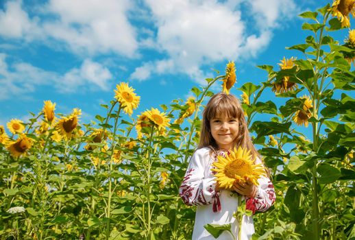 A child in a field of sunflowers in an embroidered shirt. Ukrainian. Selective focus.