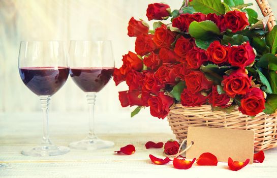 A bouquet of red roses and red wine in glasses. Valentine's Day. Selective focus. Holiday.