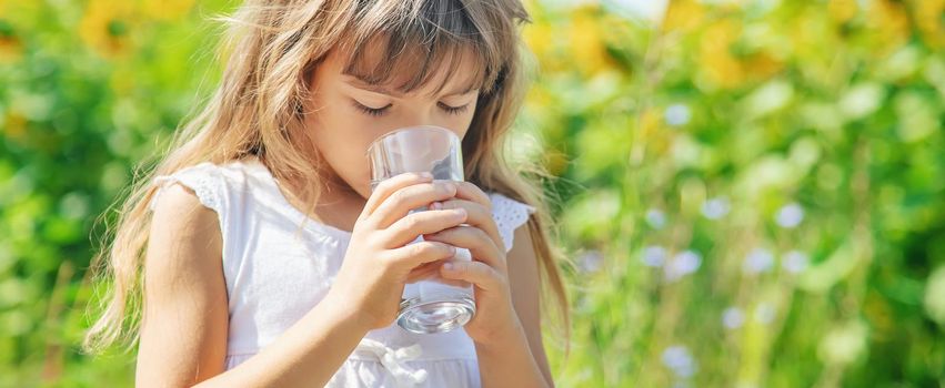 A child drinks water on the background of the field. Selective focus.