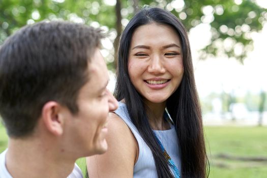 Thai woman looking with a tender expression to his couple in a park during summer