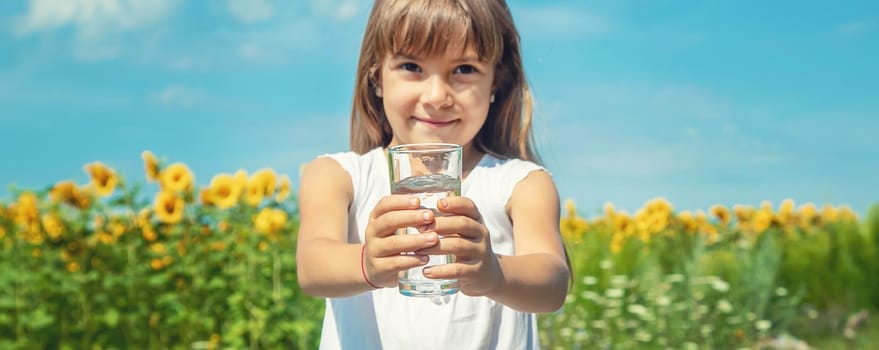 A child drinks water on the background of the field. Selective focus.