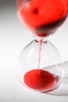 hourglass with red sand used to measure time flow, macro photography