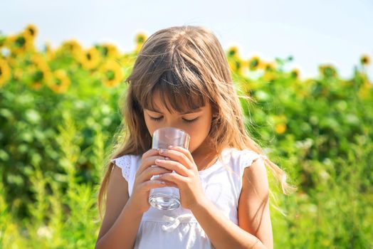 The child drinks water from a glass. Selective focus. Food.