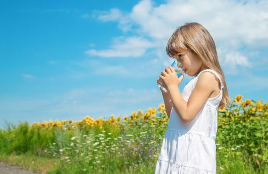 A child drinks water on the background of the field. Selective focus.