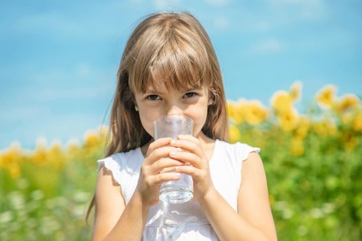 A child drinks water on the background of the field. Selective focus.