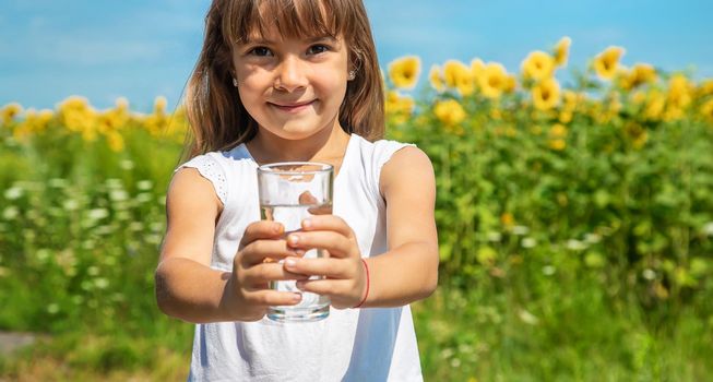 The child drinks water from a glass. Selective focus. Food.