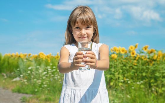 A child drinks water on the background of the field. Selective focus.