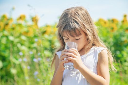 A child drinks water on the background of the field. Selective focus.