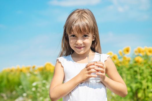 A child drinks water on the background of the field. Selective focus.