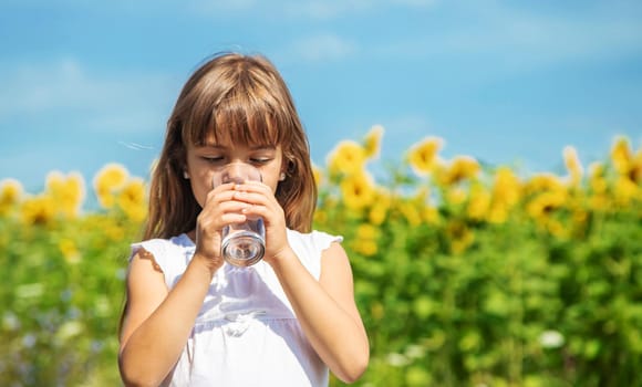 The child drinks water from a glass. Selective focus. Food.