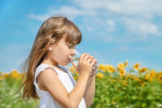 A child drinks water on the background of the field. Selective focus.