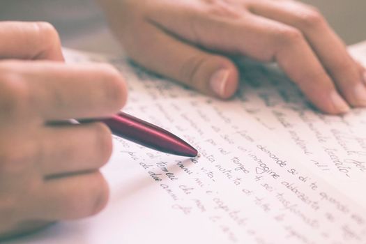 hands holding a pen while writing a letter