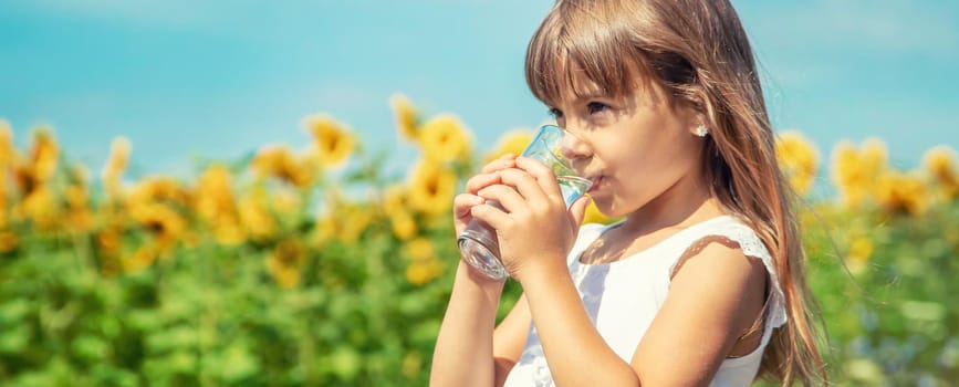 A child drinks water on the background of the field. Selective focus.