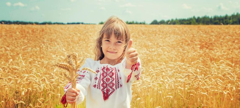 A child in a field of wheat in an embroidered shirt. Ukrainian. Selective focus.