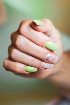 Woman's hands with nails decorated with bright glitter