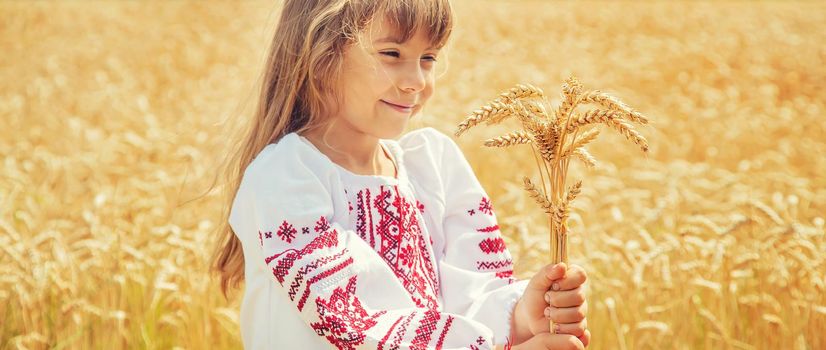 A child in a field of wheat in an embroidered shirt. Ukrainian. Selective focus.