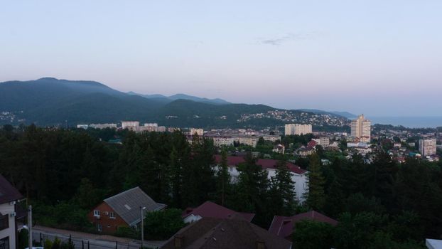 LAZAREVSKOE, SOCHI, RUSSIA - MAY, 27, 2021: Panorama of sunset in the mountains. A magical view of the sea and small town from the observation deck.