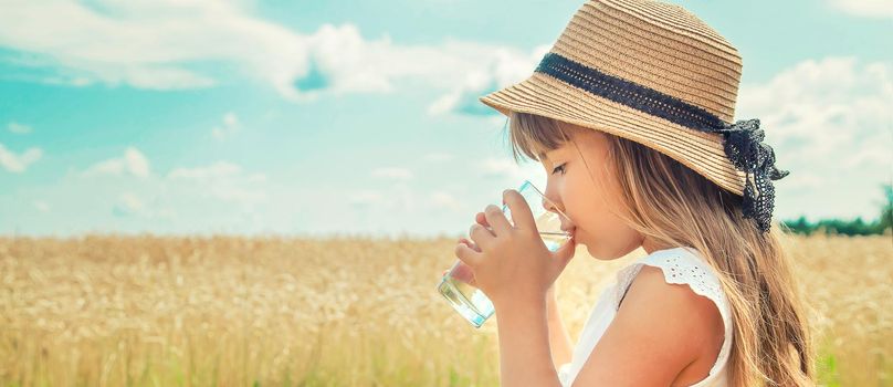 A child drinks water on the background of the field. Selective focus.