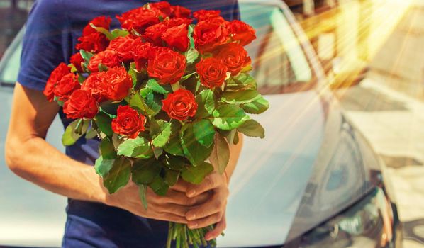 A bouquet of red roses in the hands of a man. Selective focus. Holiday.