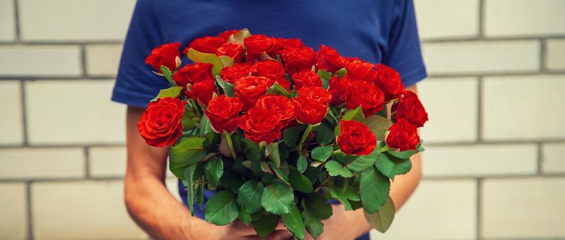 A bouquet of red roses in the hands of a man. Selective focus. Holiday.