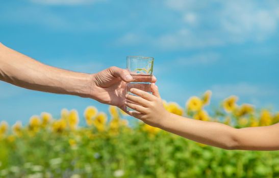 The father gives the child water in the background of the field. Selective focus. nature