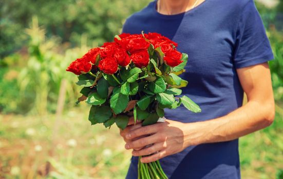 A bouquet of red roses in the hands of a man. Selective focus. Holiday.