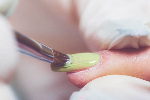 Nail beautician at work while performing the decoration and maintenance of a client's nails