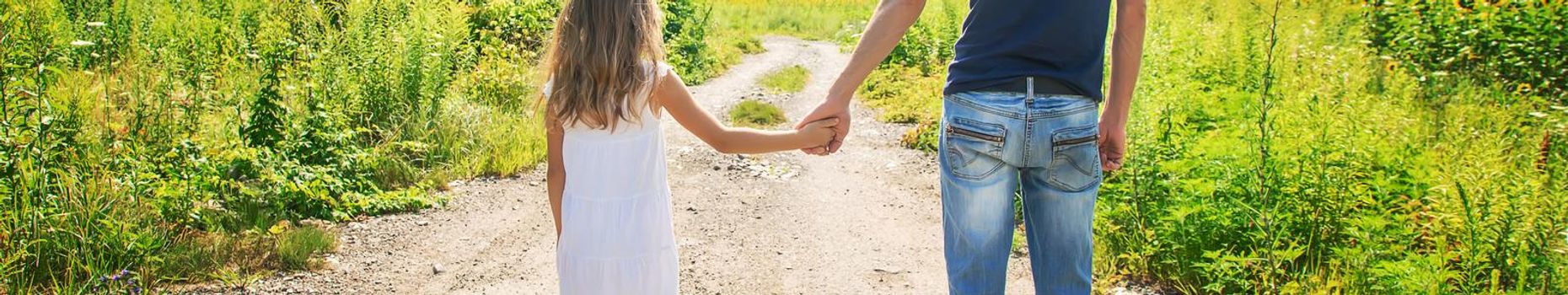 Father and daughter walk holding hands. Selective focus. nature.