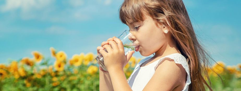 A child drinks water on the background of the field. Selective focus.