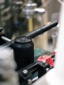 Vertical photo with focus on a black can of craft beer packaged in a canning factory