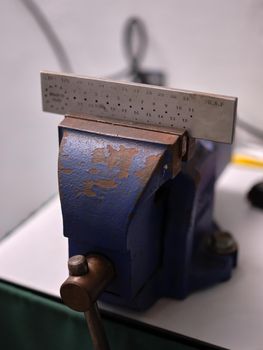 Vertical image of a vise holding a wire drawplate in a jewelry workshop.