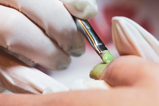 Nail beautician at work while performing the decoration and maintenance of a client's nails