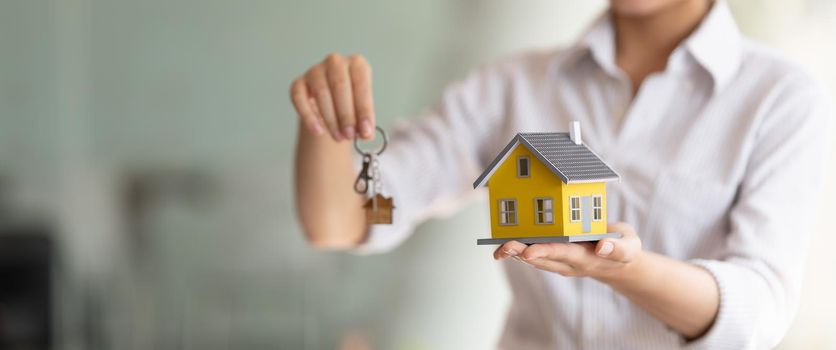 Cropped shot of real estate agent handing keys and home model