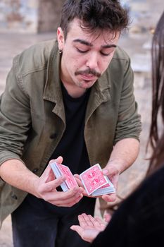 Vertical photo of a street magician splitting a pack of cards in two to perform a magic trick.