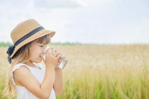 A child drinks water on the background of the field. Selective focus.